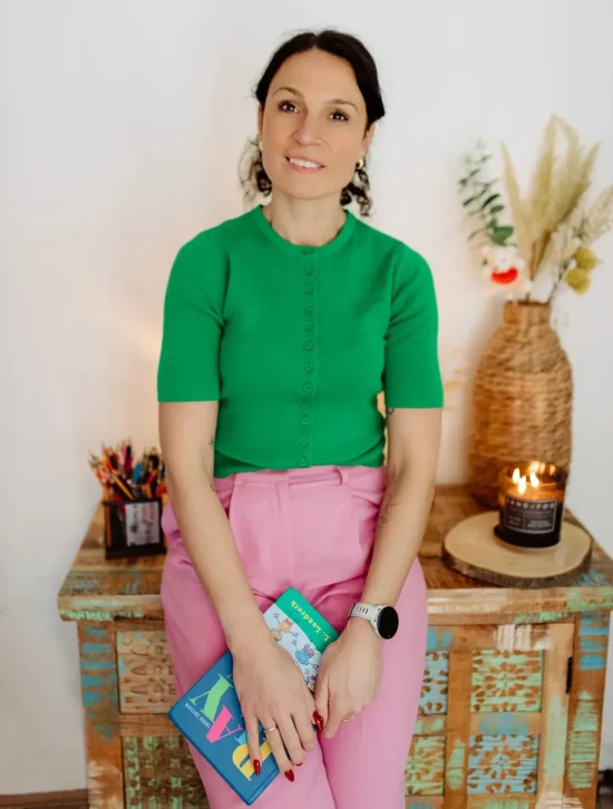 Kam standing and smiling in a green top.